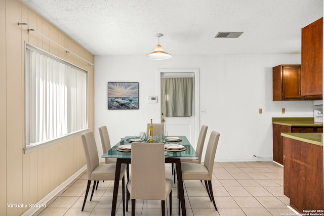 tiled dining area featuring wooden walls and a textured ceiling