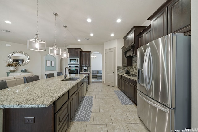 kitchen with appliances with stainless steel finishes, decorative backsplash, pendant lighting, sink, and a spacious island