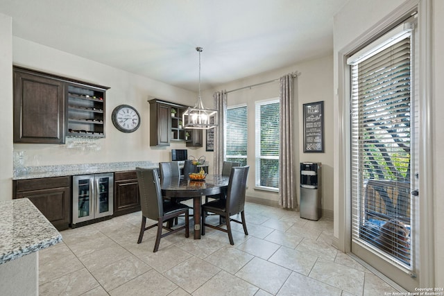 dining space with light tile patterned floors, wine cooler, and a notable chandelier