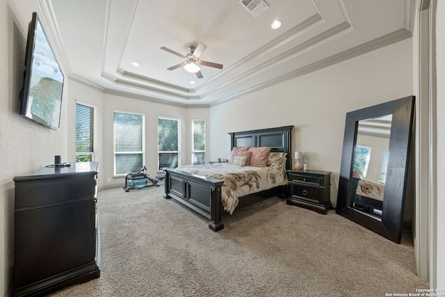 carpeted bedroom with multiple windows, ornamental molding, a tray ceiling, and ceiling fan