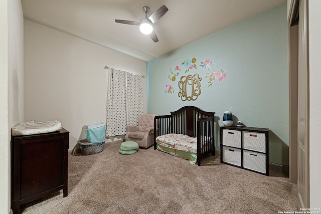 bedroom with light colored carpet, ceiling fan, and a nursery area