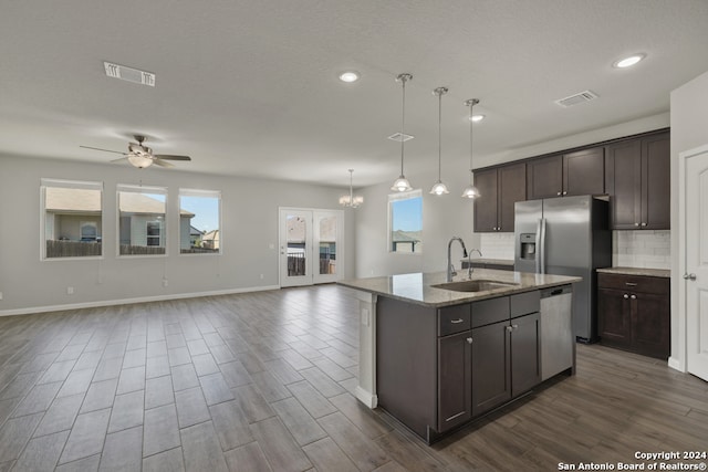 kitchen with sink, stainless steel dishwasher, a center island with sink, decorative light fixtures, and dark hardwood / wood-style flooring