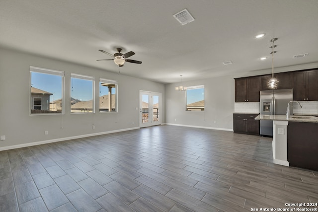 kitchen featuring dark brown cabinetry, decorative light fixtures, stainless steel fridge, and wood-type flooring