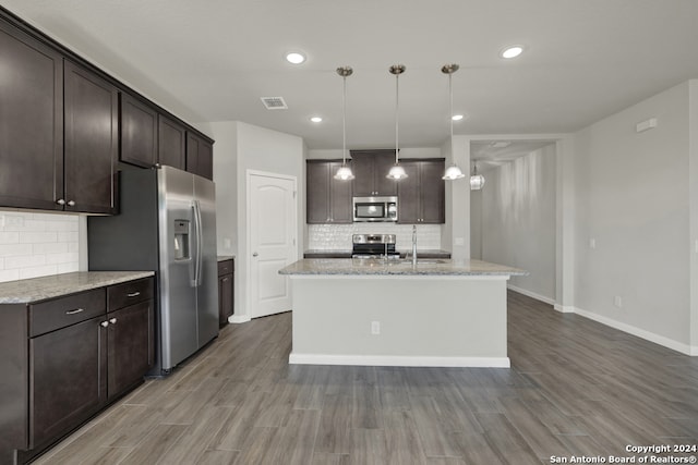 kitchen featuring a center island with sink, wood-type flooring, stainless steel appliances, and decorative light fixtures