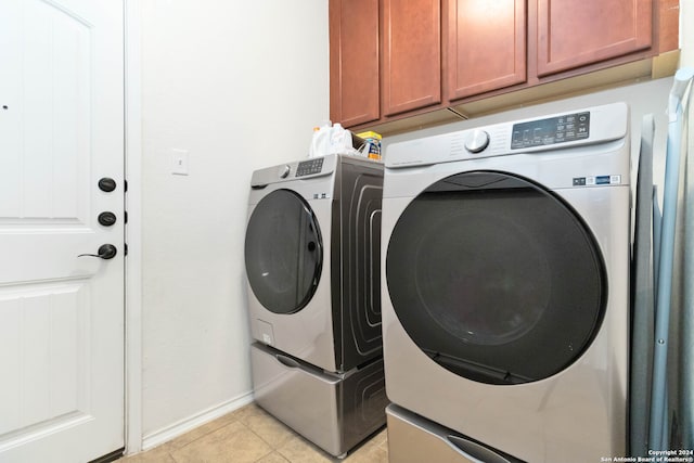 laundry room featuring light tile patterned floors, cabinets, and washer and dryer