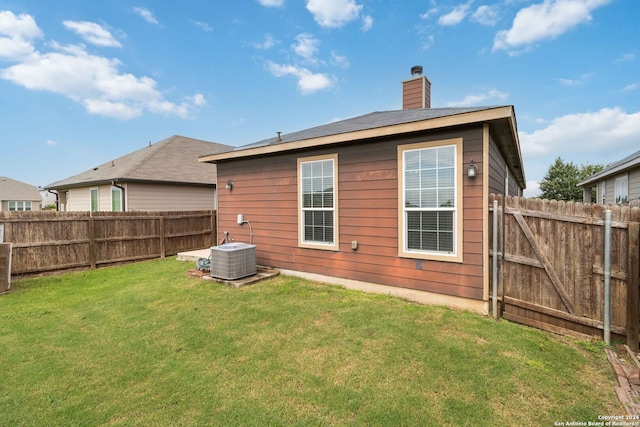 rear view of property featuring cooling unit and a yard