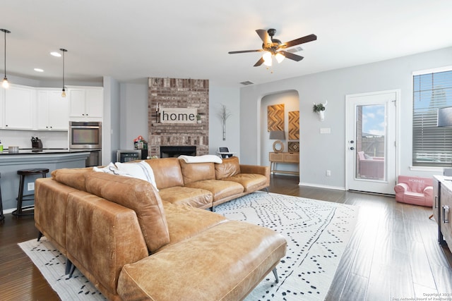 living room featuring ceiling fan, a fireplace, and dark hardwood / wood-style flooring