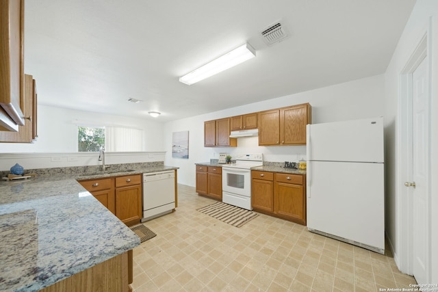 kitchen featuring light stone countertops, white appliances, and sink