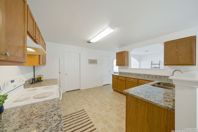 kitchen with light stone counters, white electric range, sink, and kitchen peninsula