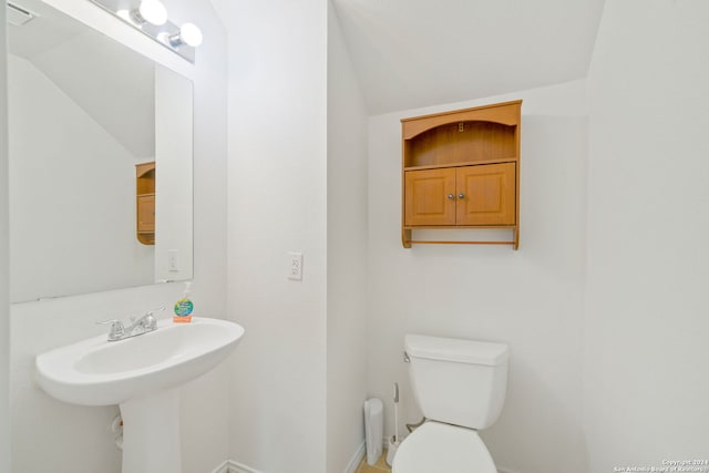 bathroom featuring lofted ceiling, toilet, and sink