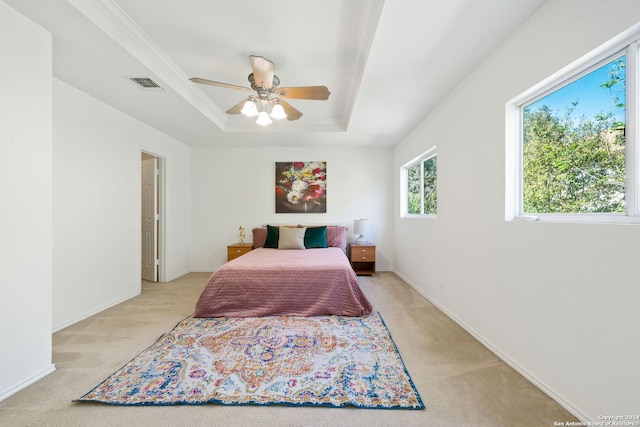 carpeted bedroom with ornamental molding, a tray ceiling, and ceiling fan