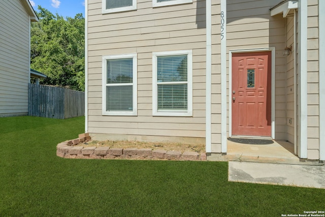 view of exterior entry featuring a lawn