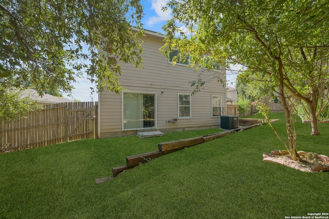 rear view of house featuring cooling unit and a yard