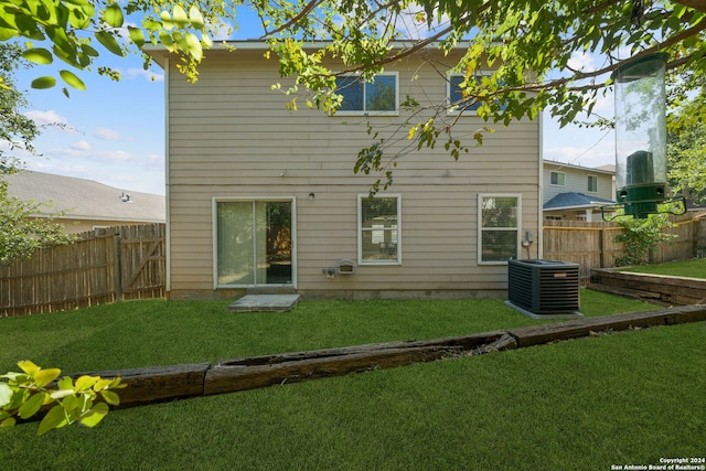 rear view of property featuring a lawn and central air condition unit