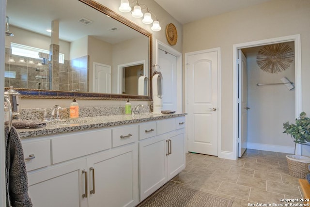 bathroom with tiled shower and vanity