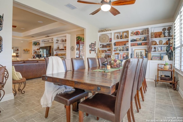 tiled dining room featuring ceiling fan, a raised ceiling, and built in features