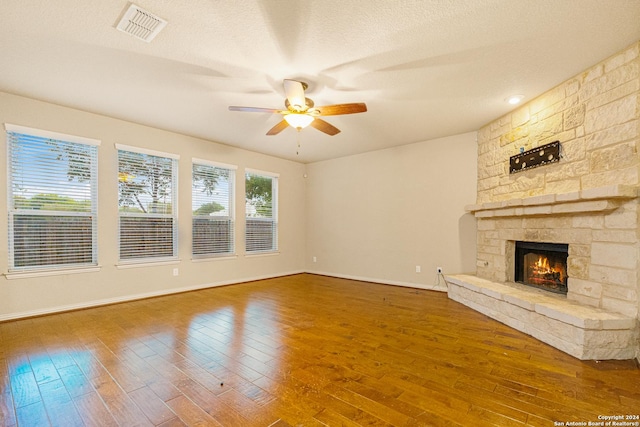 11806 Jasmine Way, San Antonio, TX 78253 - unfurnished living room with visible vents, a ceiling fan, wood-type flooring, and a stone fireplace