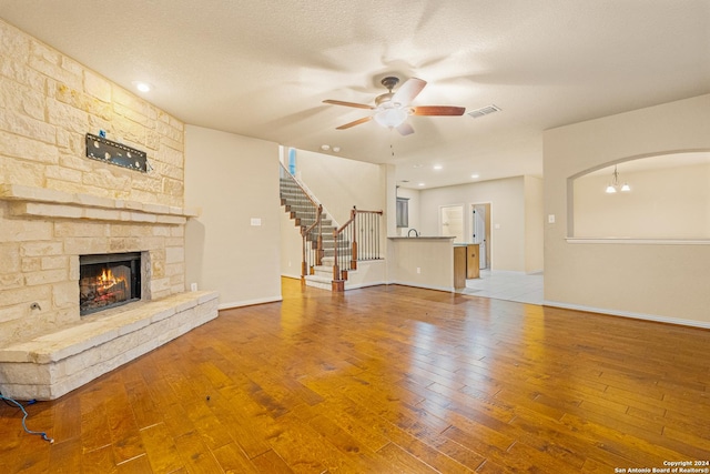 11806 Jasmine Way, San Antonio, TX 78253 - unfurnished living room featuring stairs, hardwood / wood-style floors, a stone fireplace, baseboards, and ceiling fan