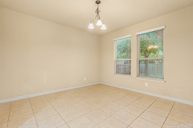 tiled empty room with an inviting chandelier