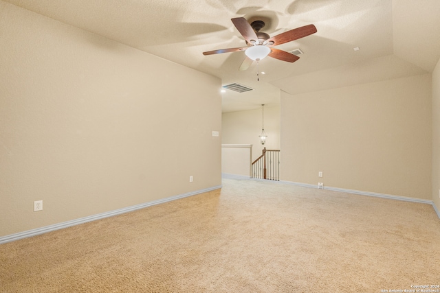 empty room with ceiling fan, carpet floors, lofted ceiling, and a textured ceiling