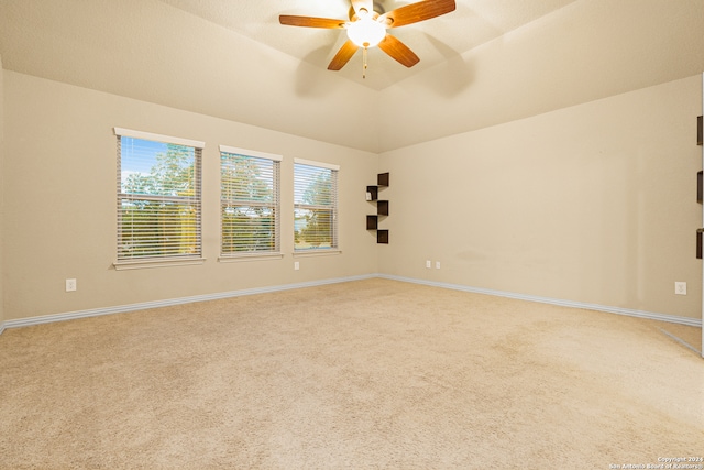 empty room with ceiling fan, vaulted ceiling, and carpet