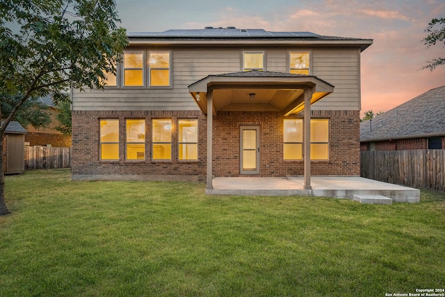 11806 Jasmine Way, San Antonio, TX 78253 - back of house at dusk with roof mounted solar panels, a yard, a patio area, and brick siding