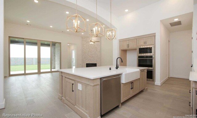 kitchen featuring pendant lighting, an island with sink, dishwasher, and light brown cabinets