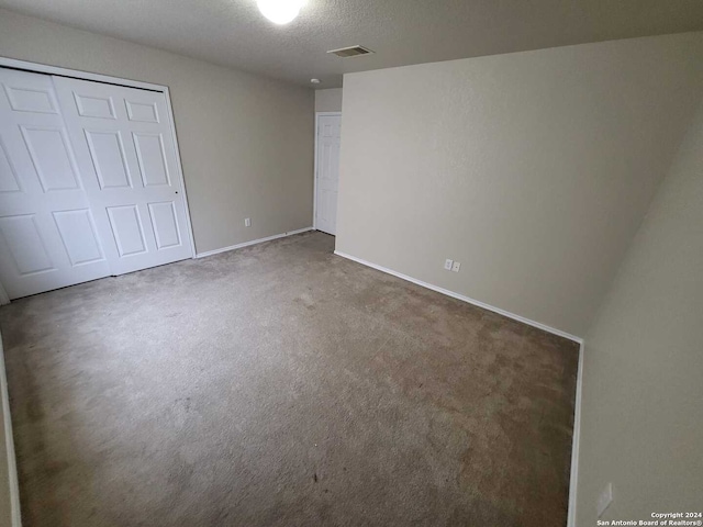 unfurnished bedroom with a textured ceiling, a closet, and carpet flooring