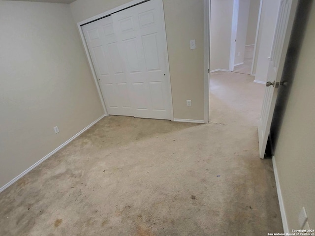 unfurnished bedroom featuring light colored carpet and a closet