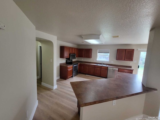 kitchen featuring a textured ceiling, sink, kitchen peninsula, light hardwood / wood-style flooring, and appliances with stainless steel finishes