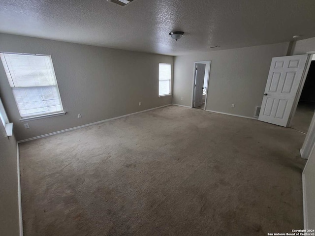 carpeted spare room with a textured ceiling