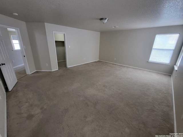 carpeted spare room featuring a wealth of natural light and a textured ceiling