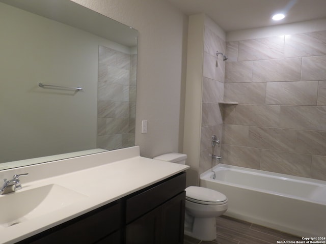 full bathroom with hardwood / wood-style flooring, vanity, toilet, and tiled shower / bath