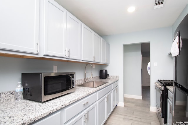 kitchen with white cabinets, appliances with stainless steel finishes, light wood-type flooring, and sink