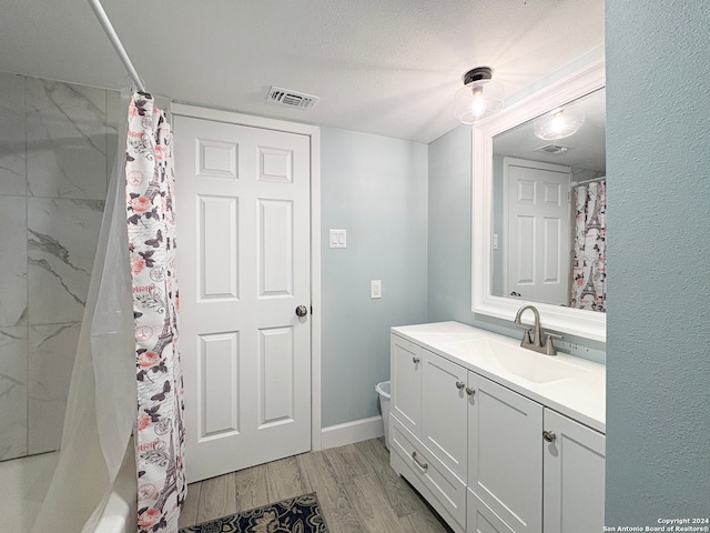 bathroom featuring a textured ceiling, walk in shower, hardwood / wood-style flooring, and vanity