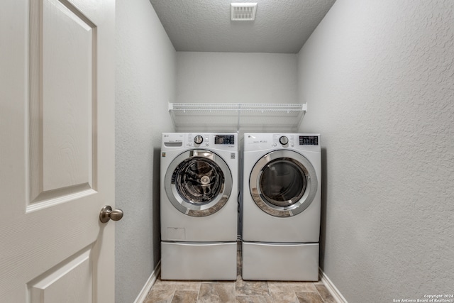 washroom featuring washing machine and clothes dryer and a textured ceiling