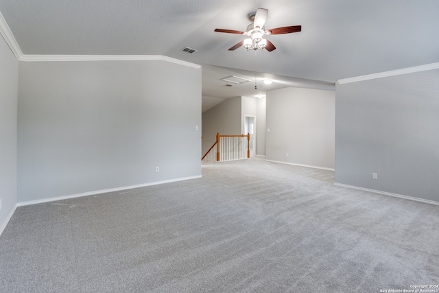 carpeted empty room featuring ceiling fan, ornamental molding, and vaulted ceiling