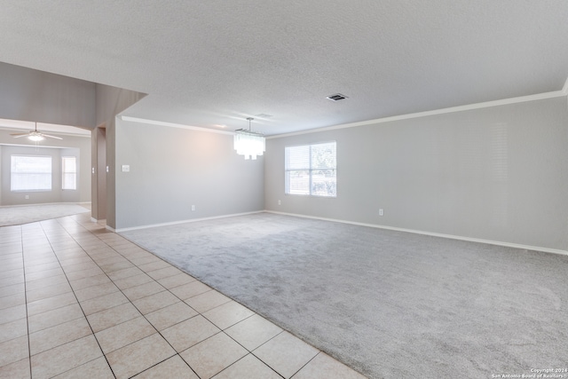 spare room featuring a textured ceiling, crown molding, ceiling fan, and light colored carpet