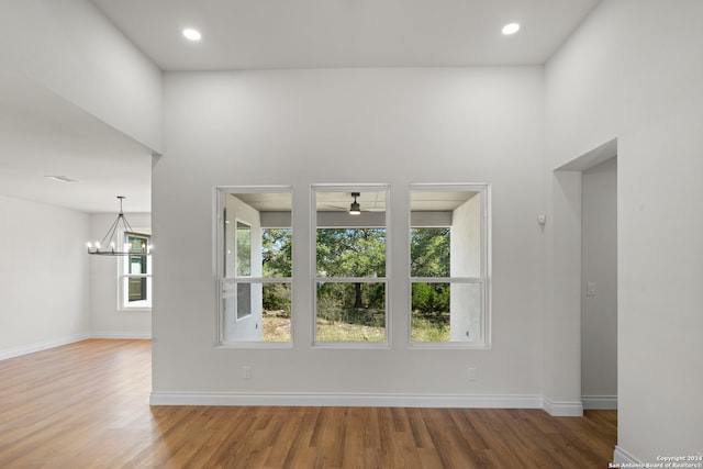 unfurnished living room featuring hardwood / wood-style flooring and ceiling fan with notable chandelier