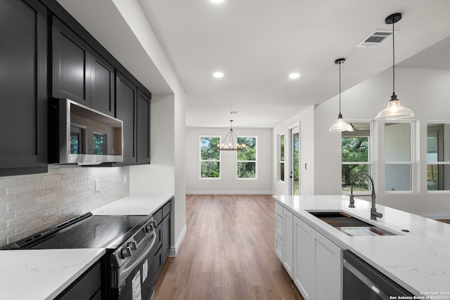 kitchen featuring appliances with stainless steel finishes, backsplash, light stone countertops, pendant lighting, and dark hardwood / wood-style floors