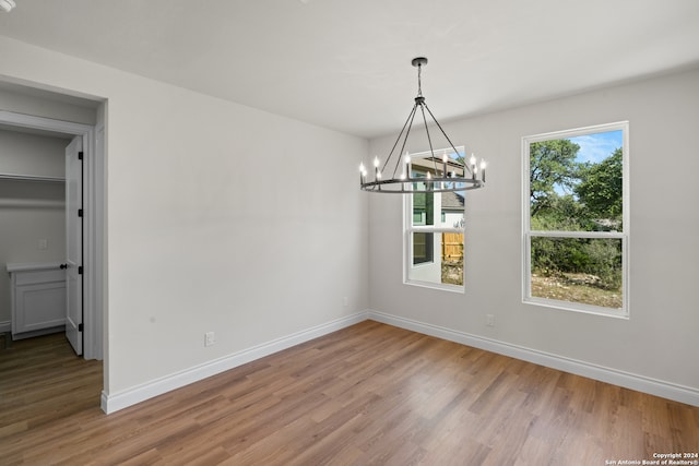 unfurnished dining area with wood-type flooring and an inviting chandelier