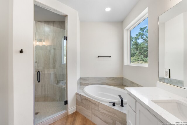 bathroom with wood-type flooring, independent shower and bath, and vanity