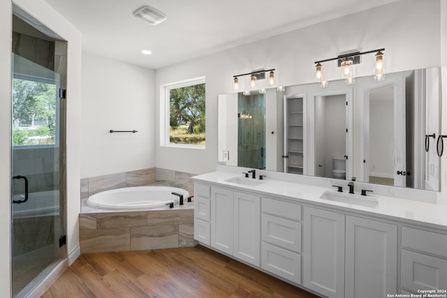 full bathroom featuring vanity, shower with separate bathtub, toilet, and hardwood / wood-style flooring