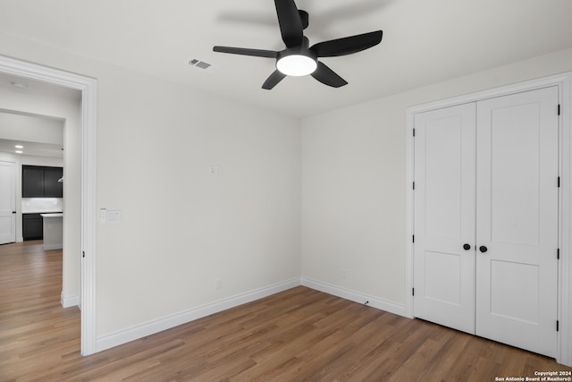 unfurnished bedroom featuring ceiling fan, a closet, and wood-type flooring