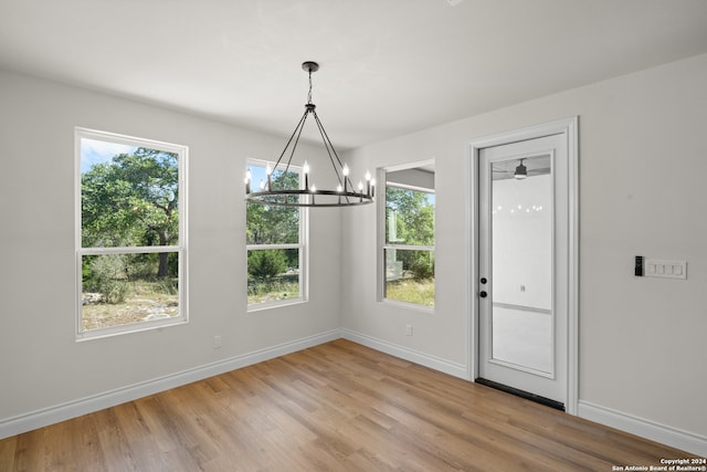 unfurnished dining area with wood-type flooring and an inviting chandelier