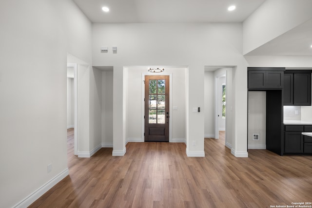 foyer entrance with light hardwood / wood-style flooring and a towering ceiling