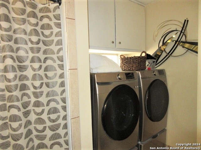 laundry area featuring washer and clothes dryer and cabinets