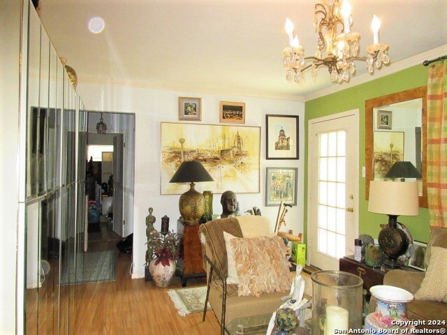 living area featuring hardwood / wood-style floors, a notable chandelier, and ornamental molding