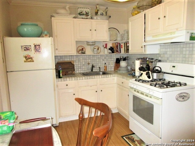 kitchen with decorative backsplash, white appliances, white cabinets, and sink