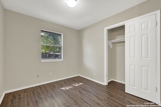 unfurnished bedroom featuring a closet and dark wood-type flooring